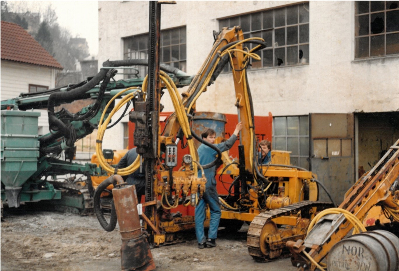 Fra Salhus våren 1987, Montabert 9.95 borerigg i bakgrunnen. Midt i bildet Atlas Roc 302, bygd om til enbommer med Tamrock L400 bormaskin